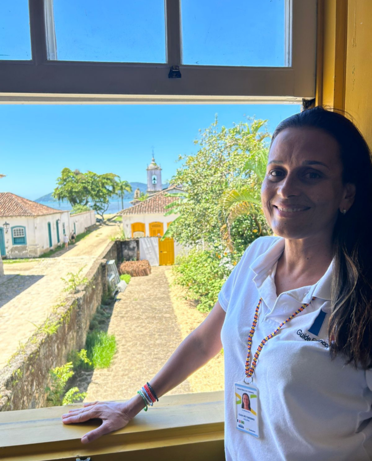 Helena, guide francophone certifiée par le Ministère du Tourisme, à la fenêtre de la Casa do Turismo de Paraty avec vue sur le centre historique colonial et la baie